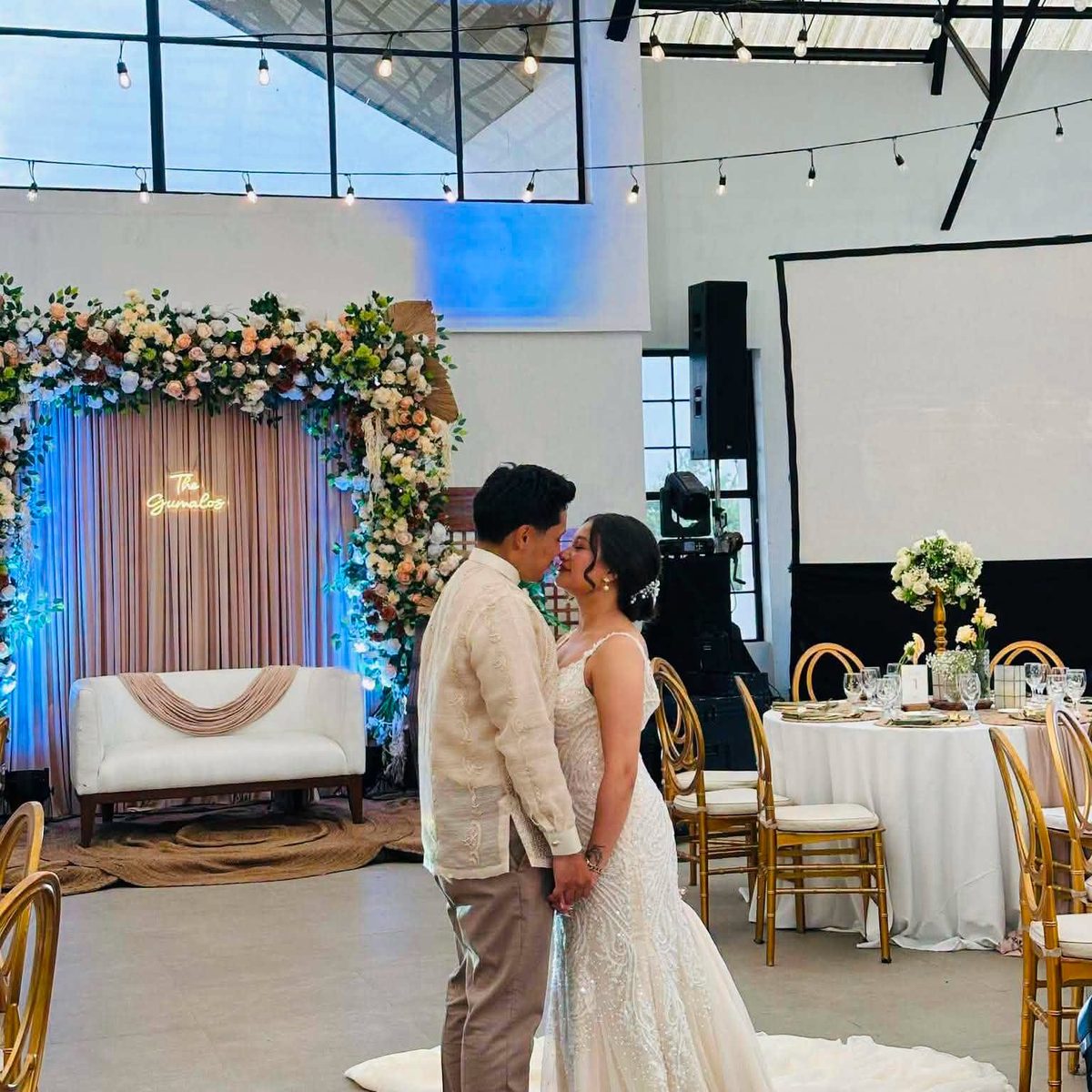 A couple exchanging vows before a floral altar lit in blue, coordinated by GO Events.