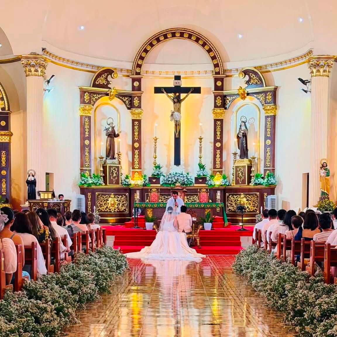 A bride walking down a cathedral aisle lined with white florals, at a GO Events wedding.