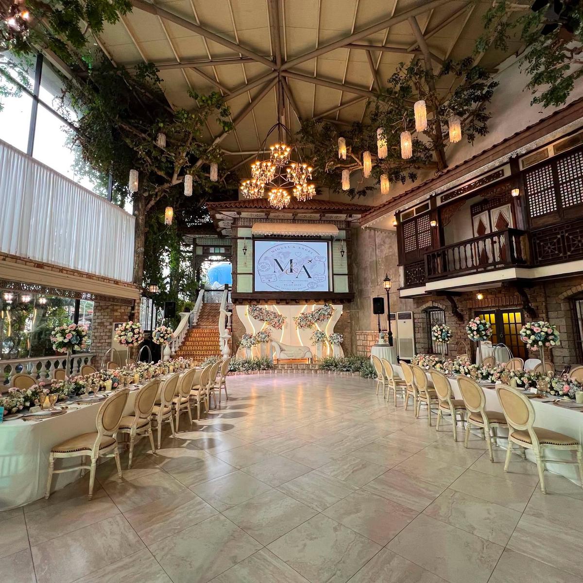 A long reception table under string lights in a heritage-style hall, coordinated by GO Events.