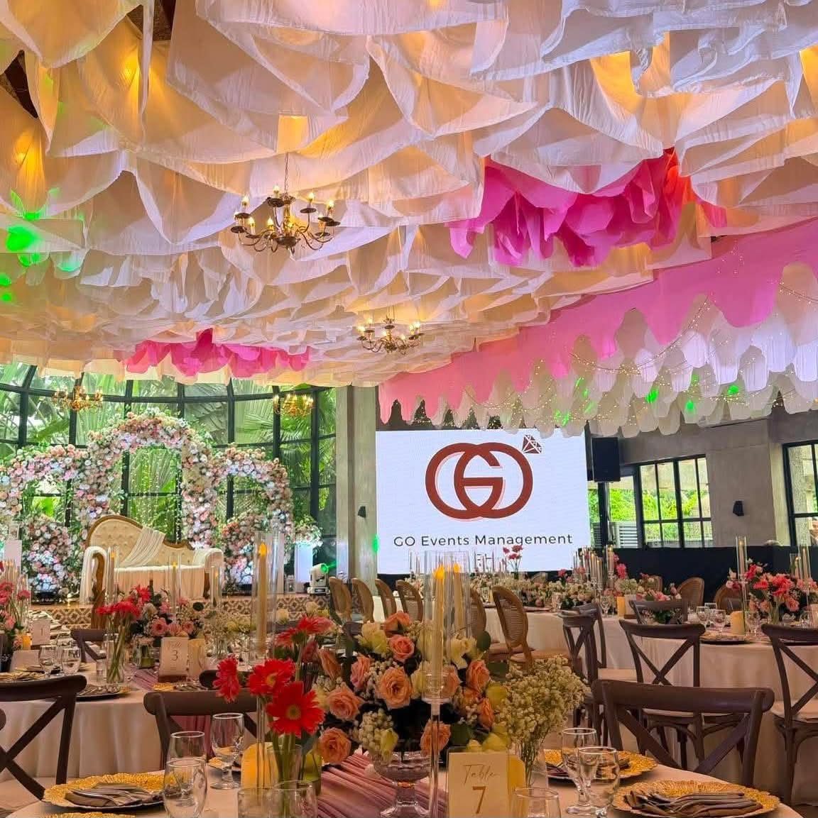 A reception venue draped in soft pink fabric, styled for a wedding coordinated by GO Events.