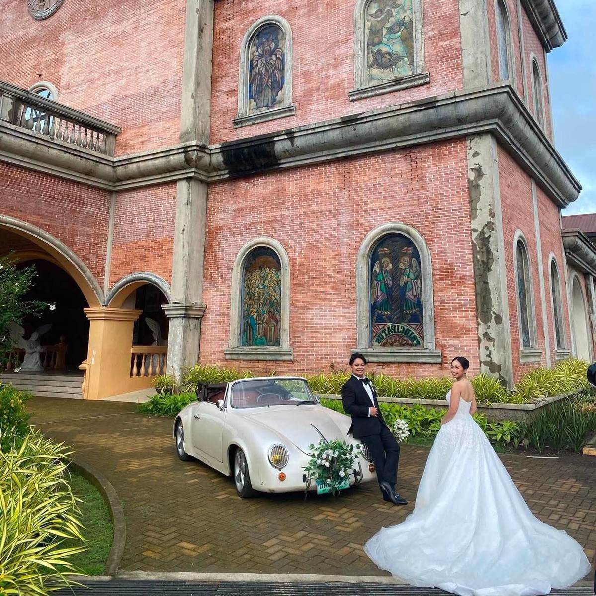 A bride and groom beside a vintage car outside a heritage church, at a GO Events wedding.