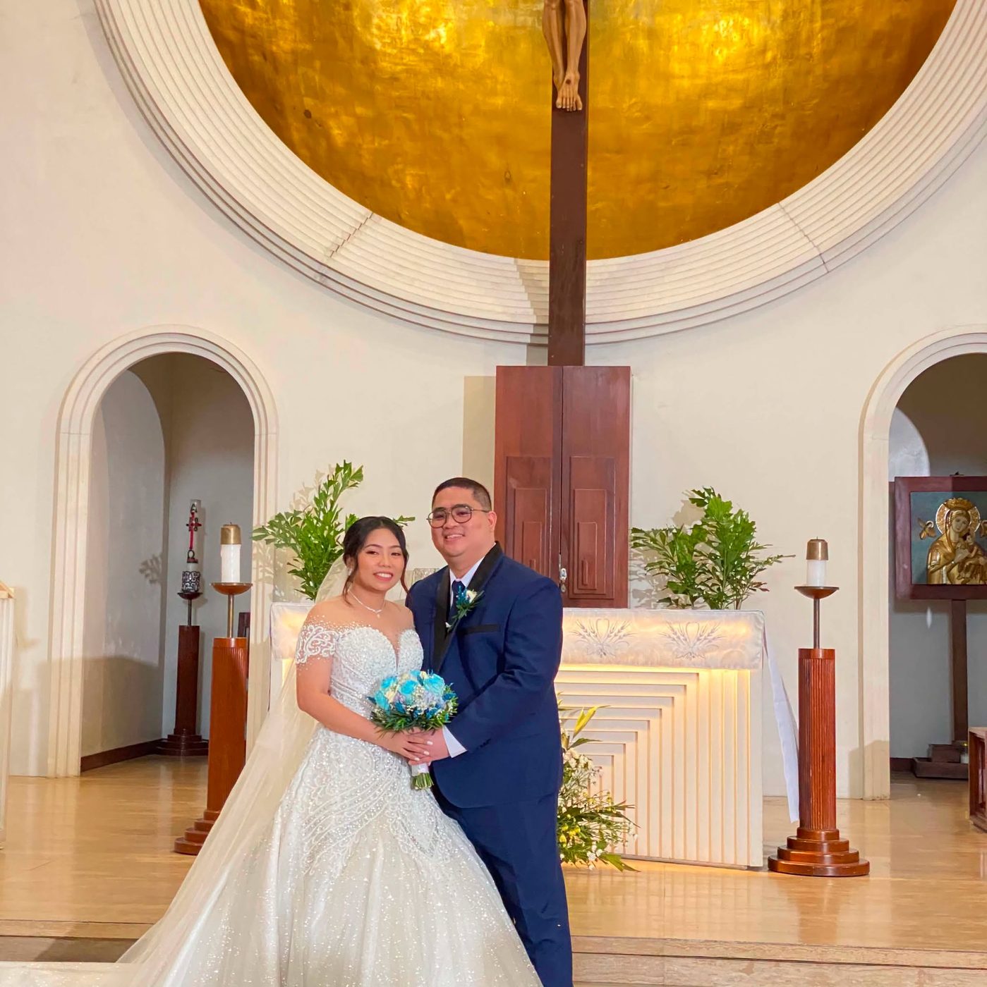 A couple embracing under a floral arch beneath a glass dome ceiling, at a wedding coordinated by GO Events.
