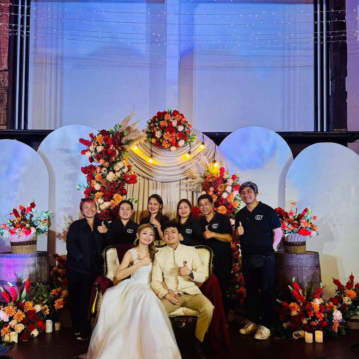 The GO Events coordination team with a newlywed couple at a barn-style reception venue.