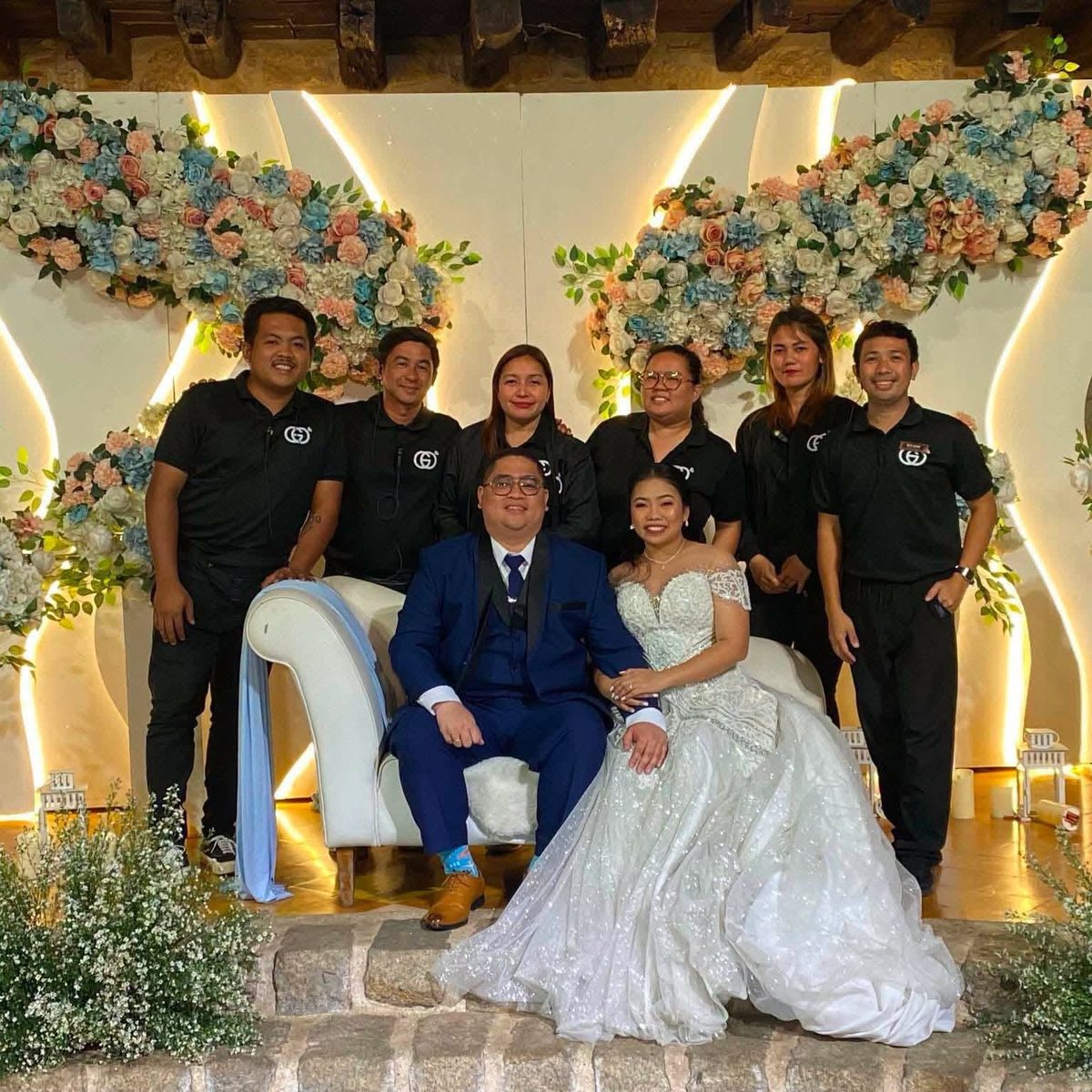 The GO Events coordination team with a newlywed couple beside a floral arch.